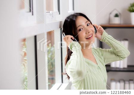 Portrait happy young woman wearing headphones listening music while standing with fun and enjoy. 122188460
