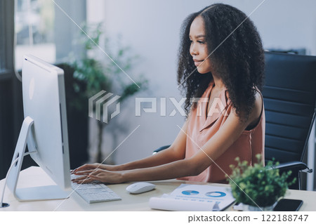 Female business person using digital tablet and laptop or remote working at home office, looking at digital tablet watching webinar, learning training, studying online seminar or video calling. 122188747