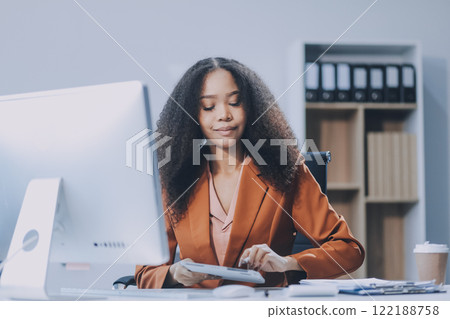 Young happy professional business woman employee sitting at desk working on laptop in modern corporate office interior. Smiling female worker using computer technology typing browsing web. Young happy professional business woman employee sitting at desk working on laptop in modern corporate office interior. Smiling female worker using computer technology typing browsing web. 122188758