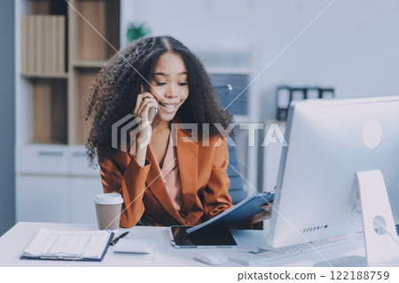 Asian woman using smart phone and laptop in office. Asian woman using smart phone and laptop in office. 122188759
