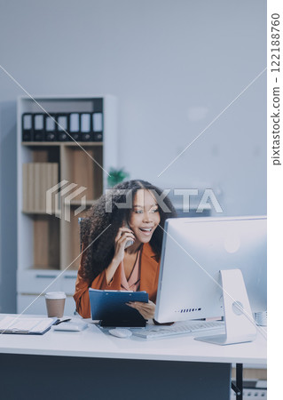 Asian woman using smart phone and laptop in office. Asian woman using smart phone and laptop in office. 122188760