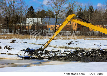 Heavy excavator machinery removes earth, snow at under construction site during winter. Heavy excavator machinery removes earth, snow at under construction site during winter. 122188886