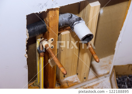 Renovation exposes plumbing pipes connections inside wall, revealing work in progress structure. Renovation exposes plumbing pipes connections inside wall, revealing work in progress structure. 122188895