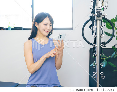 Woman using smartphone at the gym 122190055