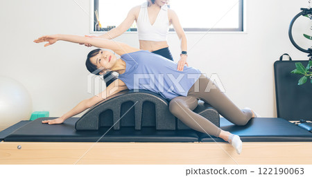 A woman taking a machine pilates lesson 122190063
