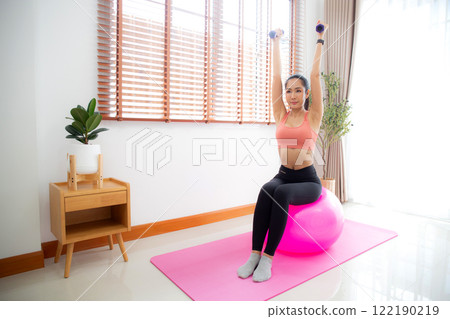 Young asian woman in sportswear workout with dumbbells for strength in living room at home. Young asian woman in sportswear workout with dumbbells for strength in living room at home. 122190219