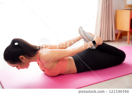 Young asian woman practicing Yoga with stretching muscle back on yoga mat in living room at home, woman exercise pilates with challenge and motivation, workout for wellness, sport and wellbeing. Young asian woman practicing Yoga with stretching muscle back on yoga mat in living room at home, woman exercise pilates with challenge and motivation, workout for wellness, sport and wellbeing. 122190398
