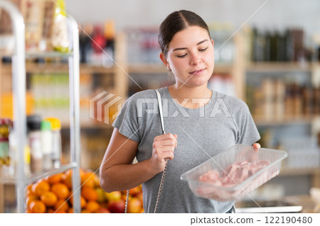 Young woman choosing lamb in grocery store 122190480