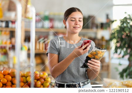 In shop European youth girl scan QR code and take reading pasta package using phone camera 122190512