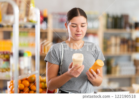 Young woman chooses mustard or mayonnaise sauces Young woman chooses mustard or mayonnaise sauces 122190518