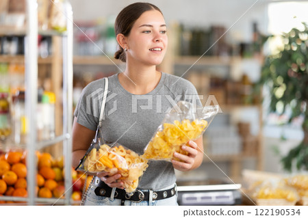 Young woman choosing chips or snack mix in grocery store 122190534