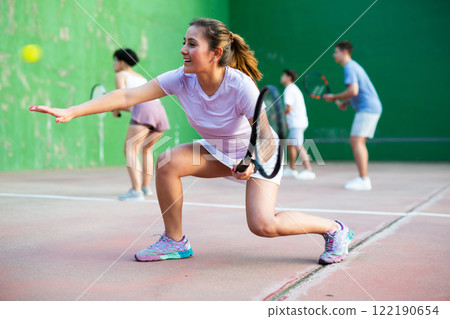 Woman serving ball during frontenis game outdoors Woman serving ball during frontenis game outdoors 122190654