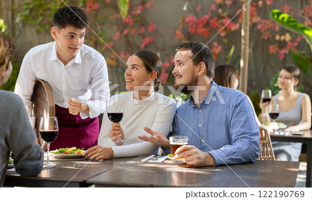Waiter talking to restaurant guests - taking orders for food and drinks Waiter talking to restaurant guests - taking orders for food and drinks 122190769