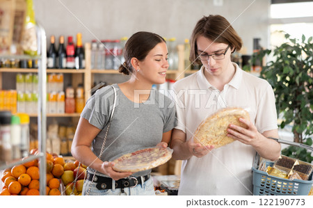 European youth girl and guy choose and buy pizza with filling in store 122190773