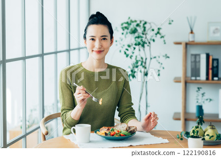 Young woman eating breakfast at home 122190816