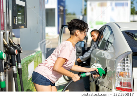 Latin woman filling up tank of her car with gasoline in gas station 122190817