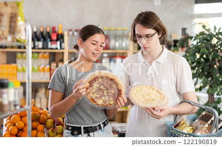 European youth girl and guy choose and buy pizza with filling in store European youth girl and guy choose and buy pizza with filling in store 122190819