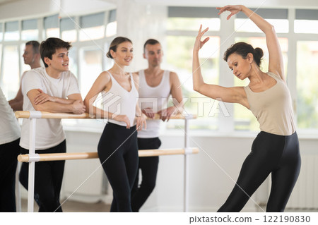 Pretty female choreographer conducting classes in ballet studio shows group correct performance of choreographic exercise 122190830