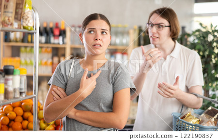 Young man quarrels with woman in grocery store 122190837