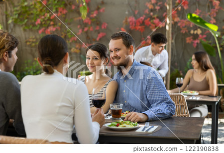 Couples of women and men eating and talking in restaurant 122190838