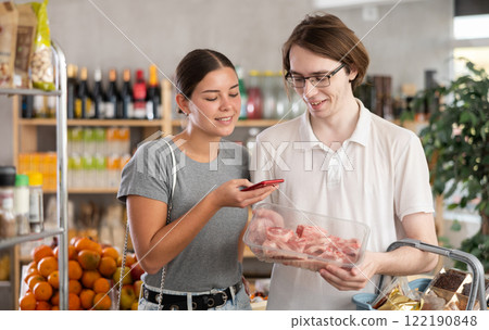 In shop youth spouses scan QR code and take reading raw pork tenderloin package using phone camera 122190848