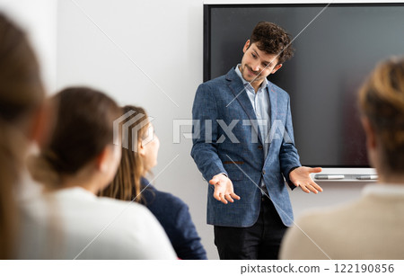Young male tutor teaching students in college classroom 122190856