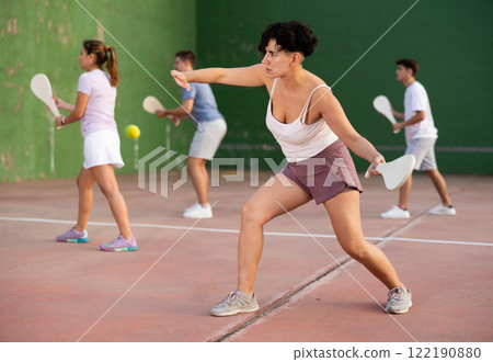 Young hispanic woman playing frontenis on open court in summer Young hispanic woman playing frontenis on open court in summer 122190880