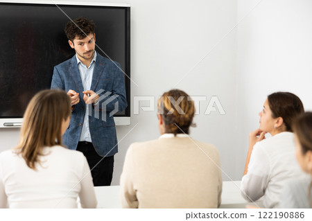 Young male teacher giving lecture to group of student 122190886