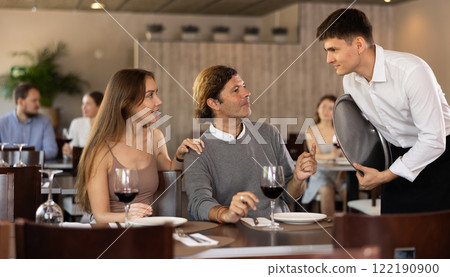 Waiter takes order from man and woman couple Waiter takes order from man and woman couple 122190900