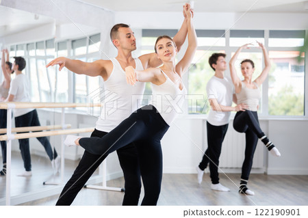Graceful couple of ballet dancers performing supports at group class Graceful couple of ballet dancers performing supports at group class 122190901