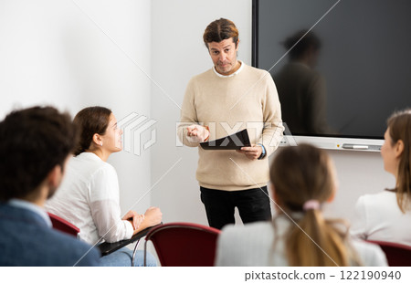 Confident male leader, trainer near interactive board talking to group of people, brainstorming, discussing ideas in auditory Confident male leader, trainer near interactive board talking to group of people, brainstorming, discussing ideas in auditory 122190940