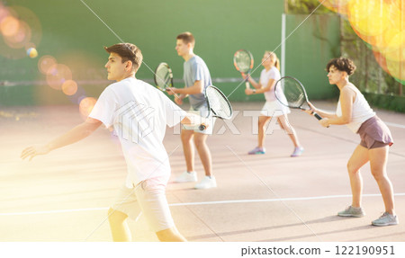 Guy hits the ball with a racket while playing frontenis on outdoor court Guy hits the ball with a racket while playing frontenis on outdoor court 122190951