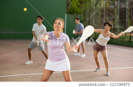 Sporty woman performing basic strokes during paleta fronton group training 122190975