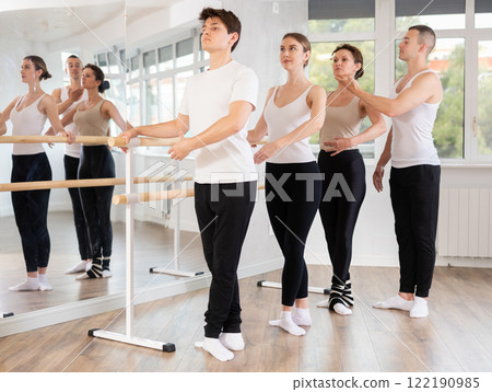 Young man trainer corrects dancers at barre 122190985