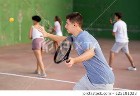 Male sportsman preparing to hit ball with racket. Frontenis game on outdoor court 122191028