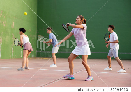 Young hispanic woman playing frontenis on open court in summer 122191060