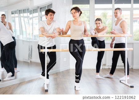 Woman with ballet class participants relaxing at barre after rehearsal Woman with ballet class participants relaxing at barre after rehearsal 122191062