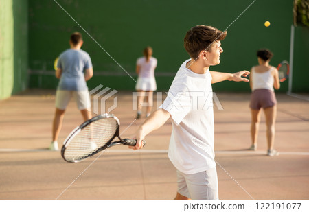 Male sportsman preparing to hit ball with racket. Frontenis game on outdoor court 122191077