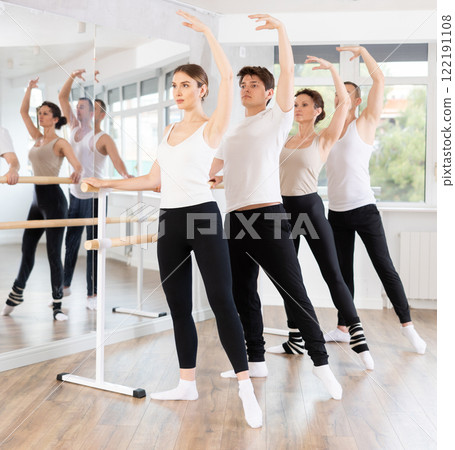 Group of dancers doing batman tandu jete at barre 122191108