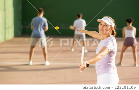 Young Latina playing pelota on open court on summer day Young Latina playing pelota on open court on summer day 122191109