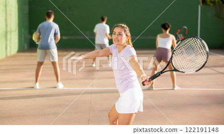 Woman serving ball during frontenis game outdoors Woman serving ball during frontenis game outdoors 122191148