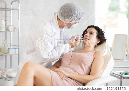 Qualified cosmetologist giving beauty injections for face skin rejuvenating and tightening for female client in aesthetic medicine office Qualified cosmetologist giving beauty injections for face skin rejuvenating and tightening for female client in aesthetic medicine office 122191153