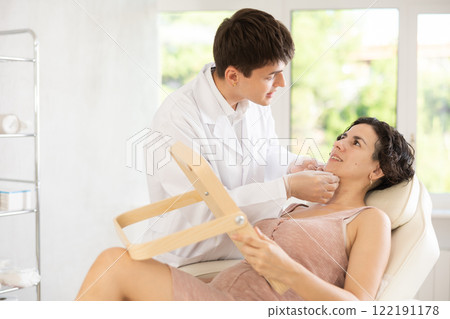 Middle-aged woman having consultation about face aesthetic while looking in the mirror Middle-aged woman having consultation about face aesthetic while looking in the mirror 122191178