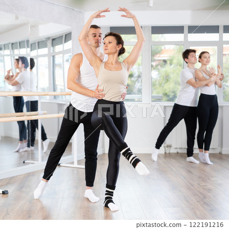 Ballet partners mastering paired technique at group class in studio Ballet partners mastering paired technique at group class in studio 122191216