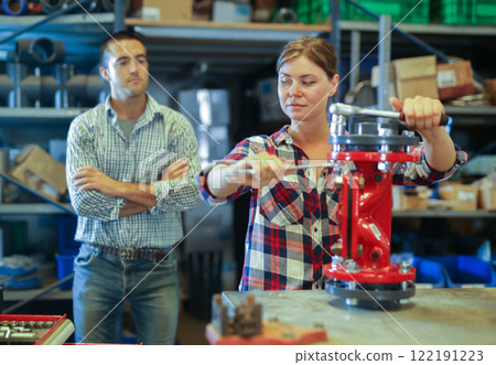 Woman assembling plumbing fixture under control of skillful man 122191223
