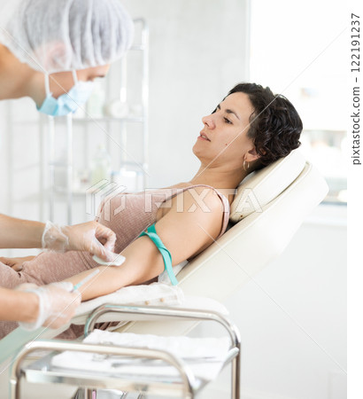 Male anesthesiologist injecting anesthetic into vein on her arm with syringe in cosmetology clinic 122191237