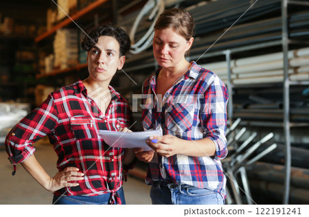 Female warehouse owner and manager keep track of products in warehouse 122191241