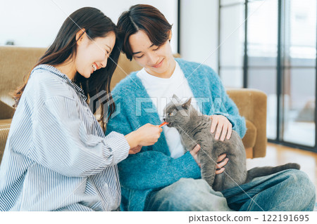 Couple giving treats to cat Couple giving treats to cat 122191695