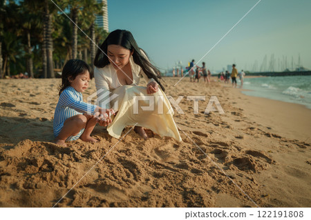 happy toddler baby girl playing sand with mother on sea beach in Pattaya, Thailand happy toddler baby girl playing sand with mother on sea beach in Pattaya, Thailand 122191808