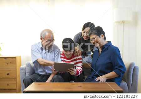 Happy Asian family having fun watching online video with Tablet in living room at home. 122193227